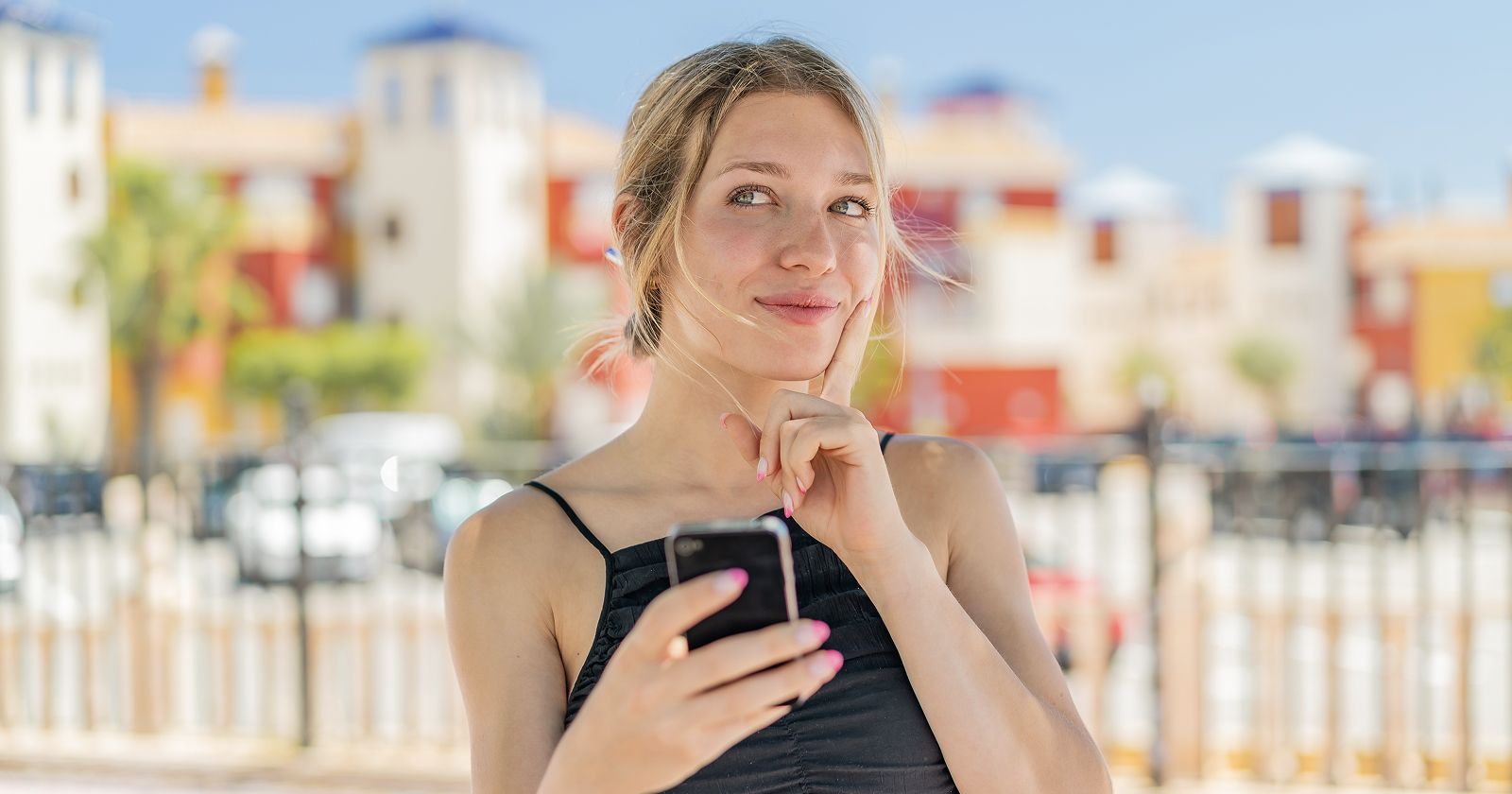 Young woman using her mobile outdoors in Spain, checking whether she has 4G or 5G coverage