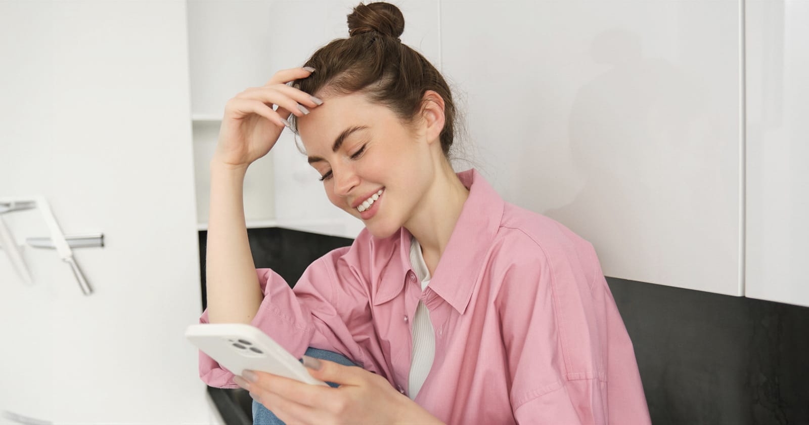 Woman in a pink shirt smiling while using her mobile phone in Spain
